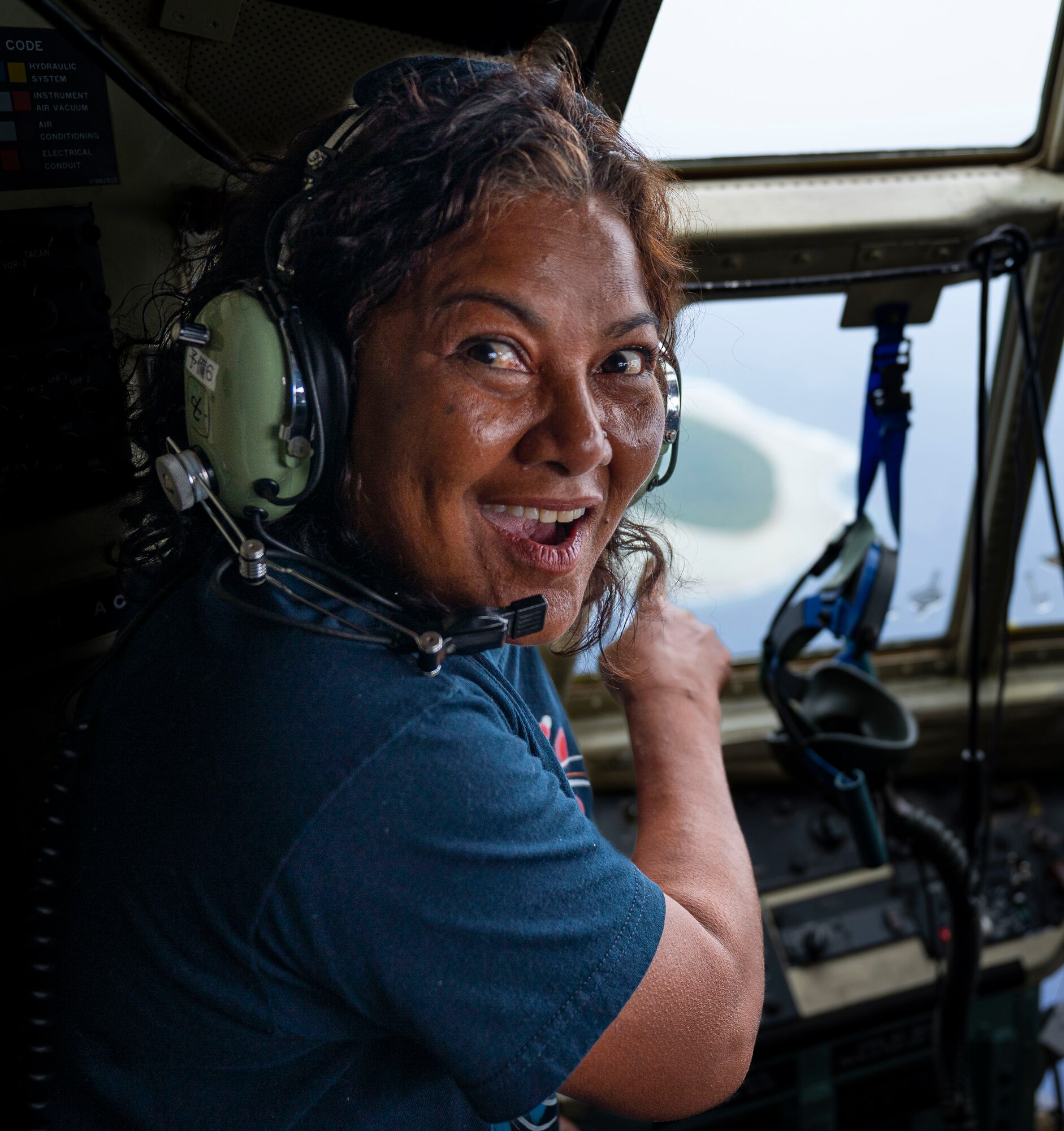Nanako Lipai, a Mokil Atoll native, points out her home island during a flight for Operation Christmas Drop 2023 (OCD 23) above the Federated States of Micronesia, Dec. 6, 2023. Established in 1952, OCD has evolved into the longest-running Department of Defense humanitarian aid and disaster relief mission, benefiting over 20 thousand islanders on 58 islands throughout the Federated States of Micronesia and the Republic of Palau. This was Lipai’s third time flying during OCD but it was the first time she got to fly to her home island to drop supply bundles. (U.S. Air Force photo by Airman 1st Class Spencer Perkins)