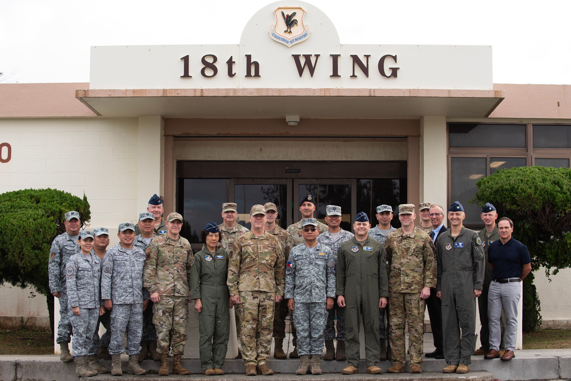 military members pose for a portrait in front of higher headquarters building
