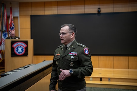 A male U.S. Army Soldier in dress uniform stands to give remarks during an award ceremony.