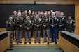 Large group of U.S. Army soldiers in dress uniform gather on a stage for a photo after an award ceremony