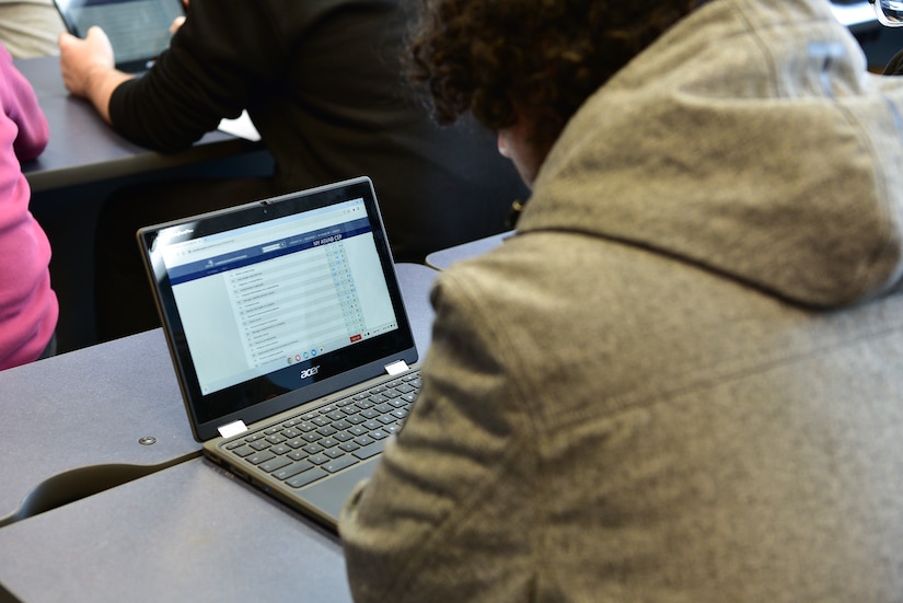 A student looks at a computer screen while seated at a desk.