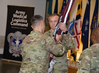 Command Sgt. Maj. Gabriel Wright accepts the Army Medical Logistics Command unit colors from Commander Col. Marc Welde during a change of responsibility ceremony Dec. 8, 2023, at Fort Detrick, Maryland. Wright is the new senior enlisted leader for AMLC, replacing outgoing Sgt. Maj. Akram Shaheed. (C.J. Lovelace)