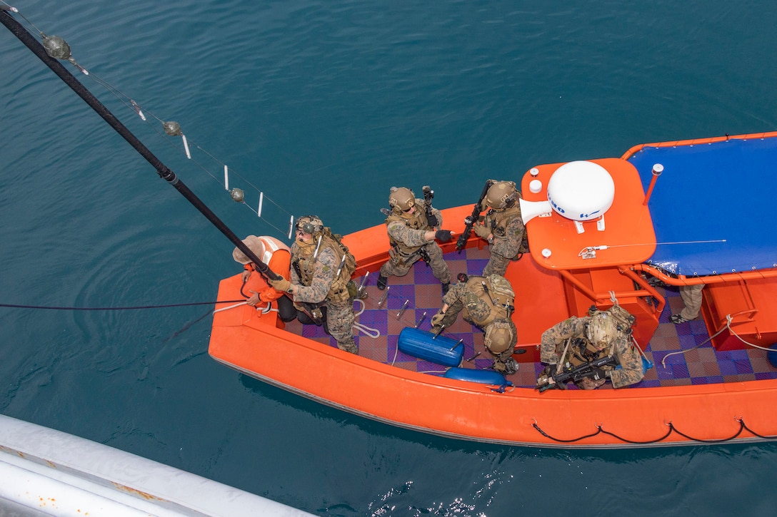 Marines are photographed from above while preparing to board a vessel from a raft.