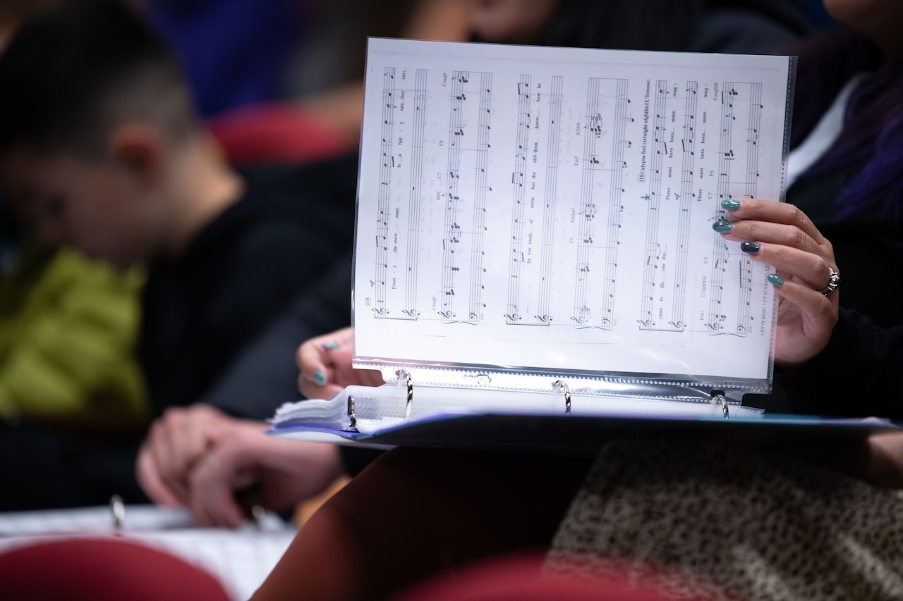 A person flips through a binder of sheet music.