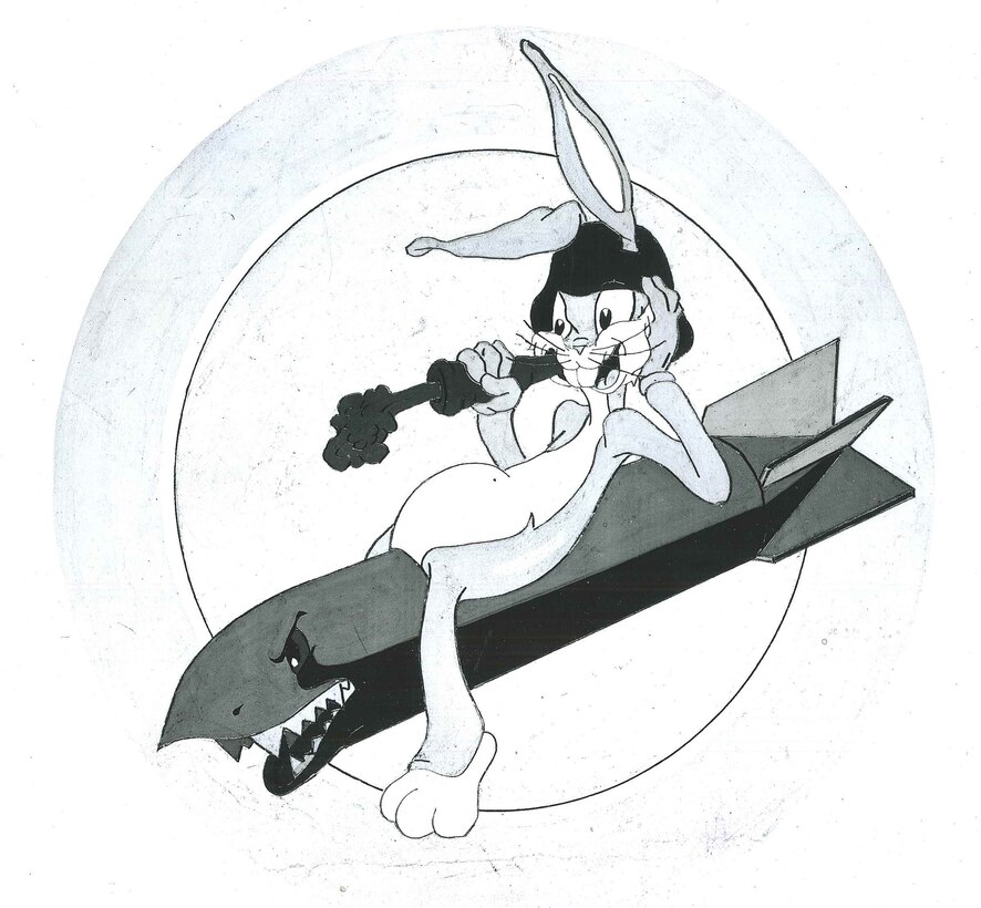 vThe black and white drawn-insignia on a round disc of VPB-103’s 	proposed insignia is pictured. It is of a “Bugs Benny”-looking rabbit lounging on top of a large bomb, with a shark-like face, teeth, and grin, eating a carrot with flames shooting out of the end of it. According to the typed letter, the “large bomb symbolizes a heavy bombardment squadron. The teeth in the nose of the bomb and the gleam in its eye depicts the effectiveness and readiness of attack”; the “rabbit would denote the speed of the planes. Large tummy represents the capacity bomb load and the open eyes and 	confident grin of the rabbit stands for alertness and confidence of success”; and the “carrot is symbolic of excellent eyesight of the crew, especially under night conditions.”  The insignia was drawn by Leon Schlessenger.