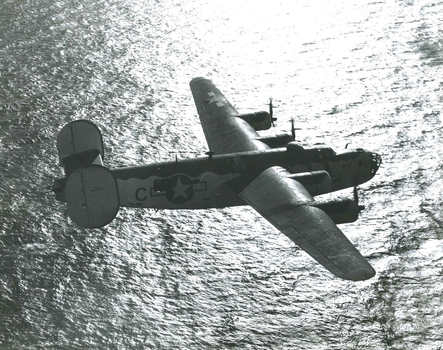 The crisp, clear black- and white-photograph of a PB4Y-1 “Liberator” airplane viewed from its starboard side, flying over the Bay of Biscay in November 1943