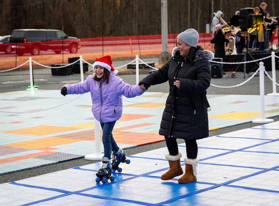 U.S. Marines and their families roller skate during the annual Quantico holiday tree lighting at the Marine Corps Exchange parking lot on Marine Corps Base Quantico, Virginia, Dec. 7, 2023. The festivities included a roller-skating rink, snowball fighting, games for children, music performances, and vendor booths all to celebrate the holiday season. (U.S. Marine Corps Photo by Lance Cpl. Kayla LeClaire)