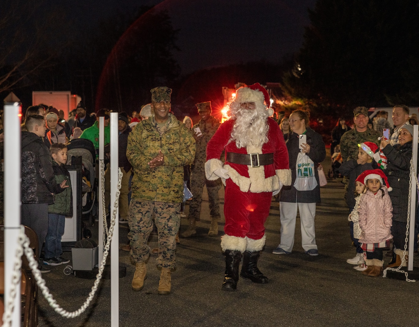 U.S. Marine Corps Col. Michael L. Brooks, base commander, Marine Corps Base Quantico, walks with Santa during the annual Quantico holiday tree lighting at the Marine Corps Exchange parking lot on Marine Corps Base Quantico, Virginia, Dec. 7, 2023. The festivities included a roller-skating rink, snowball fighting, games for children, music performances, and vendor booths all to celebrate the holiday season. (U.S. Marine Corps Photo by Lance Cpl. Kayla LeClaire)