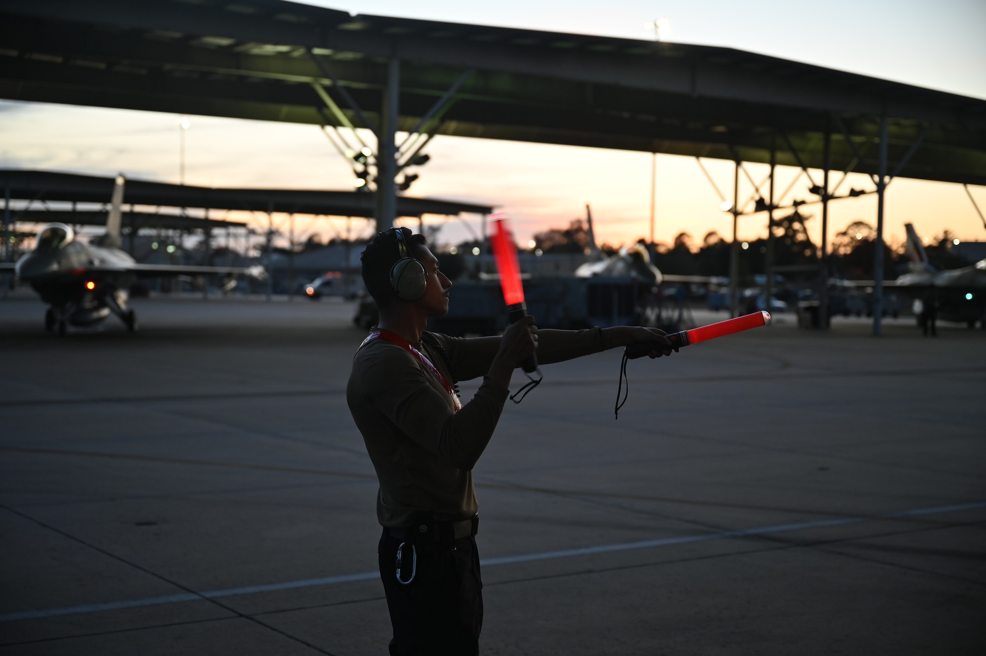 maintainer uses marshaling wands on the flightline