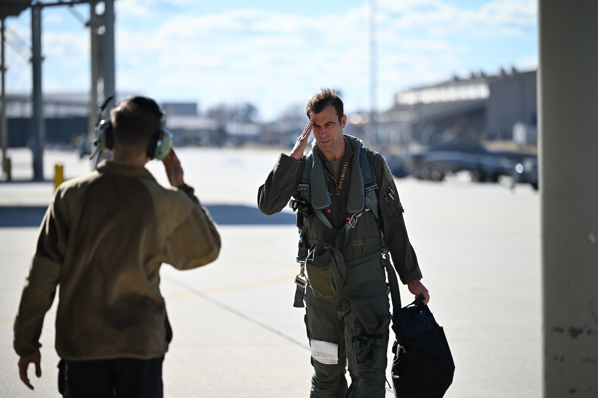 pilot salutes a maintainer on the flightline