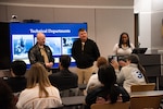 Commanding Officer Capt. Matthew L. Tardy (middle right) and Capt. Thomas Dickinson (left) speak to students