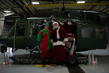 Santa Claus and an elf pose for a photo during the 54th Helicopter Squadron (HS) holiday party at Minot Air Force Base, North Dakota on December 10, 2023. At the HS holiday party, Claus takes the time to meet with children and pose for photos with members of Team Minot. (U.S. Air Force photo by A1C Luis Gomez)