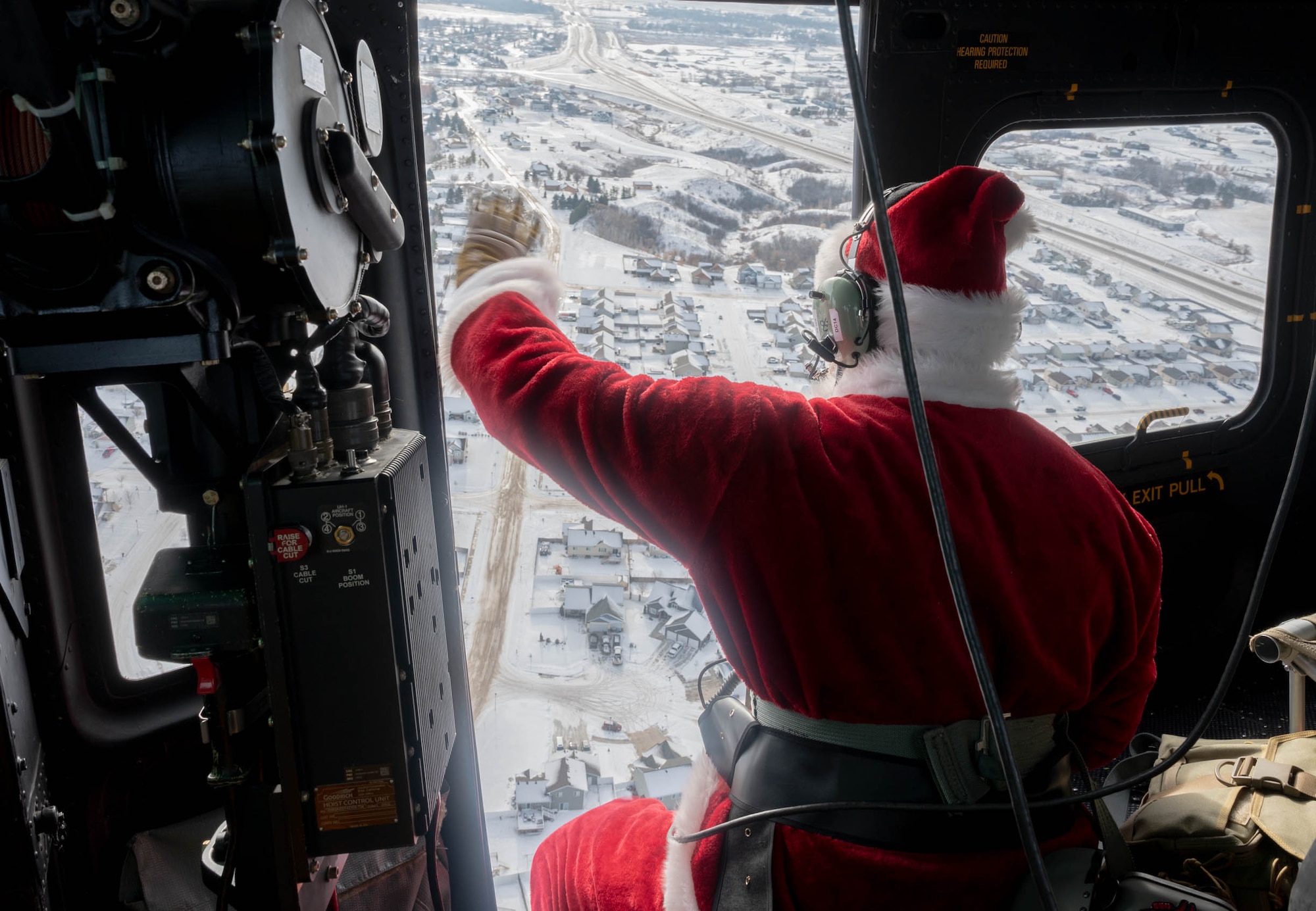 Santa Claus waves to families as he flies in a UH-1N Iroquois at Minot Air Force Base, North Dakota on December 10, 2023. Every year Claus and his elf crew greet the children of Minot Air Force Base and Minot, N.D. from the sky. (U.S. Air Force photo by A1C Luis Gomez)