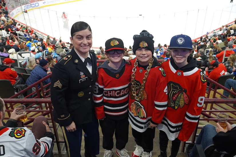 U.S. Army Reserve Sgt. Maribel Meraz, left, of the 85th U.S. Army Reserve Support Command, pauses for a photo with young game spectators after receiving an honor for her service during the Chicago Blackhawks home game, at the United Center, December 9, 2023.