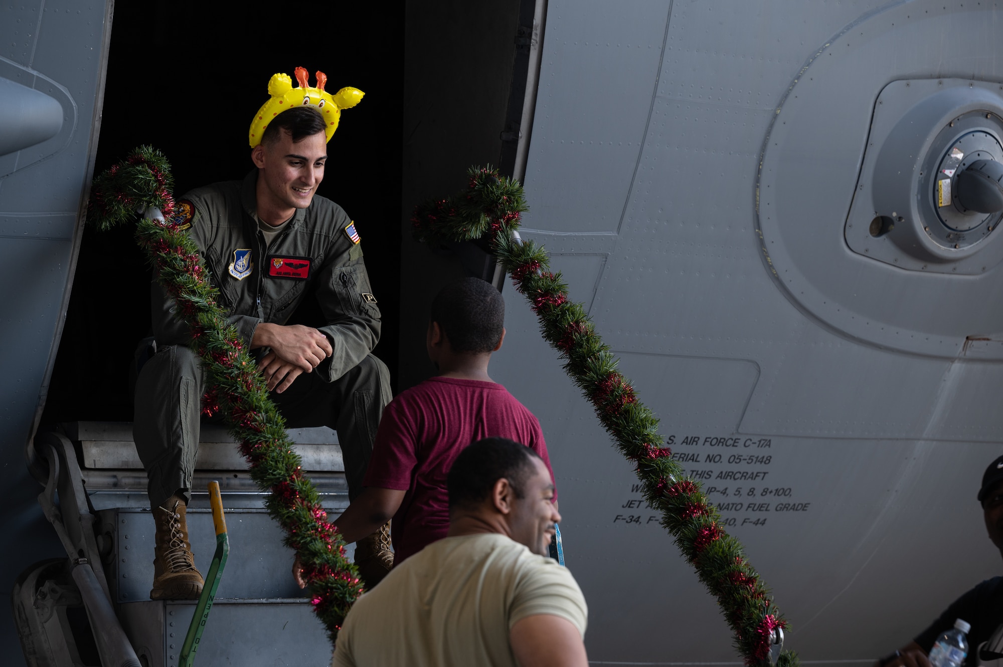 Airman 1st Class Aniel Reina Montano, 535th Airlift Squadron loadmaster, speaks with children waiting to see Santa in a C-17 Globemaster III at the 15th Wing Keiki Holiday Party at Joint Base Pearl Harbor-Hickam, Hawaii, Dec. 9, 2023. Uniformed volunteers provided teachable moments to children while inside a fuselage of a C-17 Globemaster III. (U.S. Air Force photo by Staff Sgt. Alan Ricker)