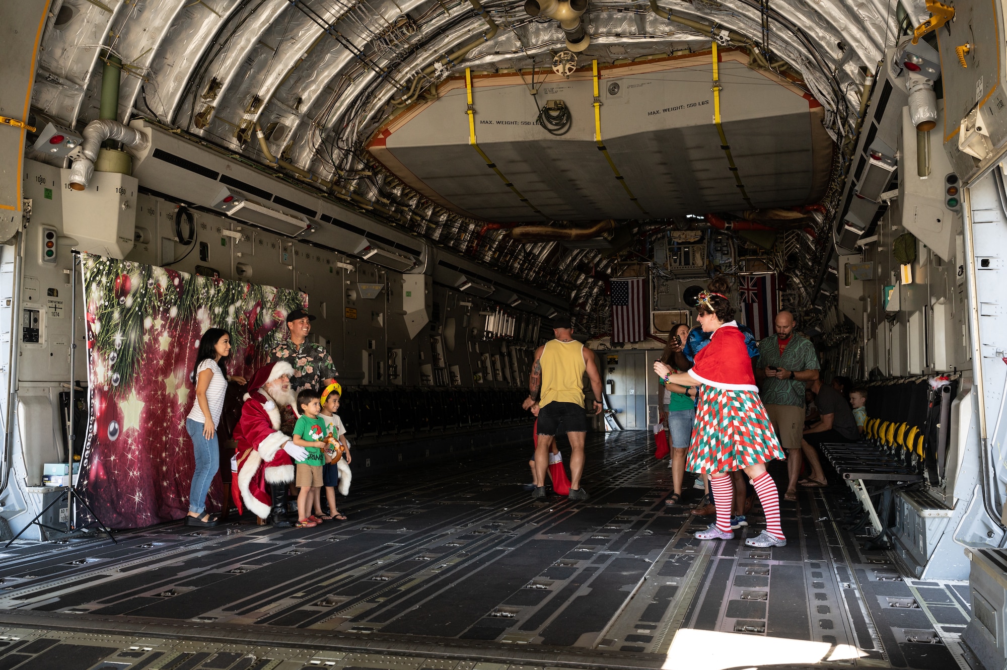 Families pose for photos with Santa inside of a C-17 Globemaster III during the 15th Wing Keiki Holiday Party at Joint Base Pearl Harbor-Hickam, Hawaii, Dec. 9, 2023. The event focused on giving military children a unique Air Force holiday celebration with their families. (U.S. Air Force photo by Staff Sgt. Alan Ricker)