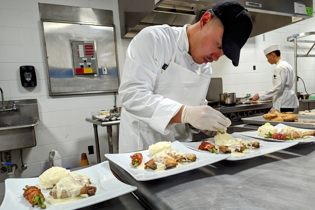 A soldier prepares a group of meals on fancy plates.