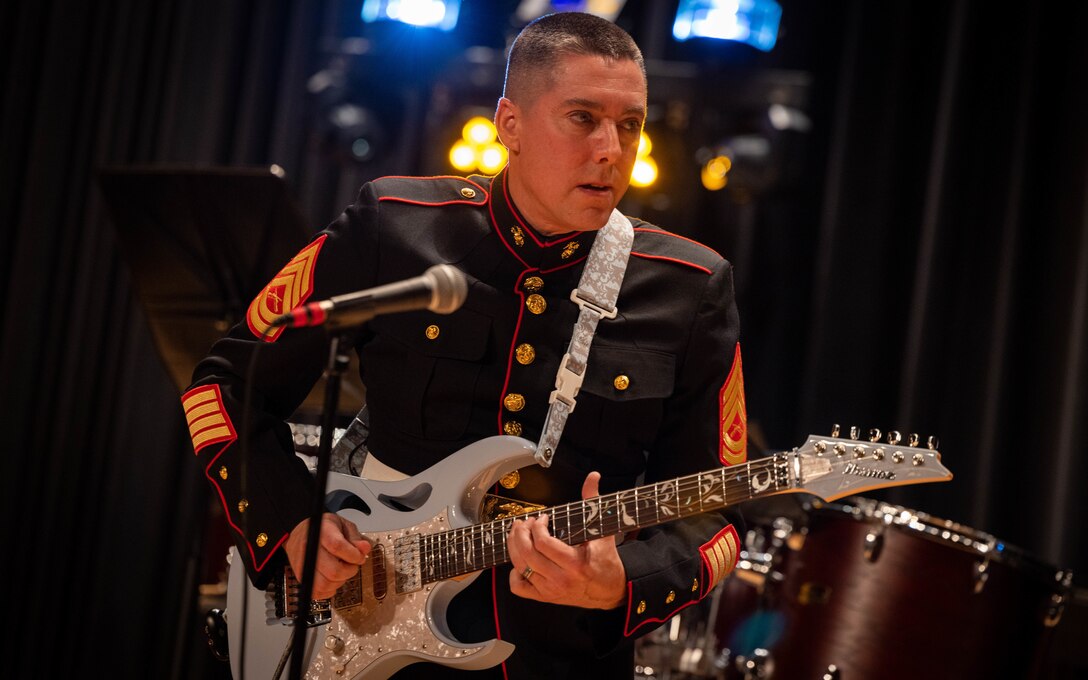 U.S. Marine Corps Gunnery Sgt. Edwardo Espinosa, assigned to the Quantico Marine Corps Rock Band, plays the guitar during the annual Holiday Concert at Little Hall on Marine Corps Base Quantico, Virginia, Dec. 10, 2023. The band’s mission is to provide musical support that will encourage community relations, enhance troop morale, and promote the Marine Corps recruiting program through its demanding performance schedule. (U.S. Marine Corps photo by Cpl. Mitchell Johnson)