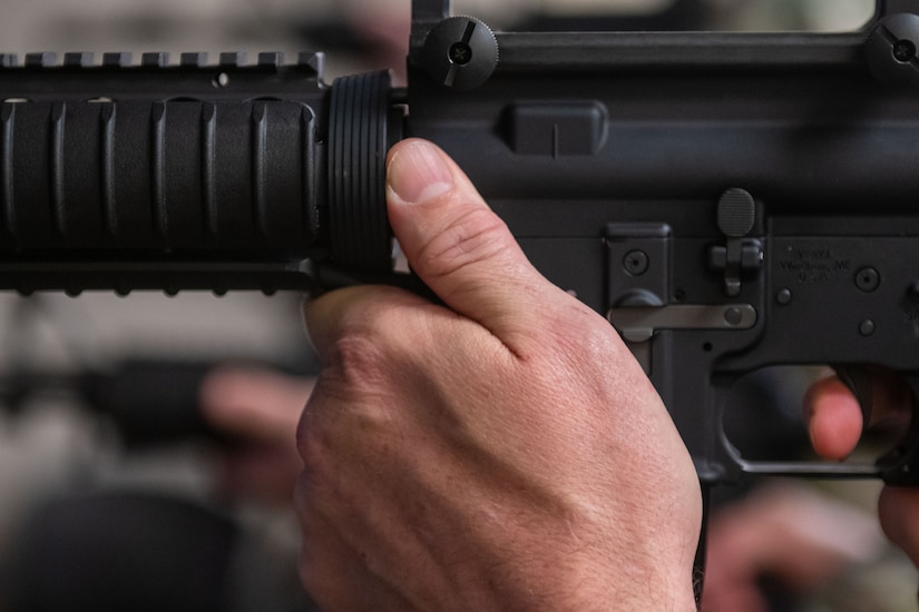 U.S. Navy Capt. Andrew Peterson, 628th Air Base Wing deputy commander and Naval Support Activity Charleston commander, prepares to shoot an M-4 rifle during firearms simulator training at Joint Base Charleston, South Carolina, Dec. 7, 2023.