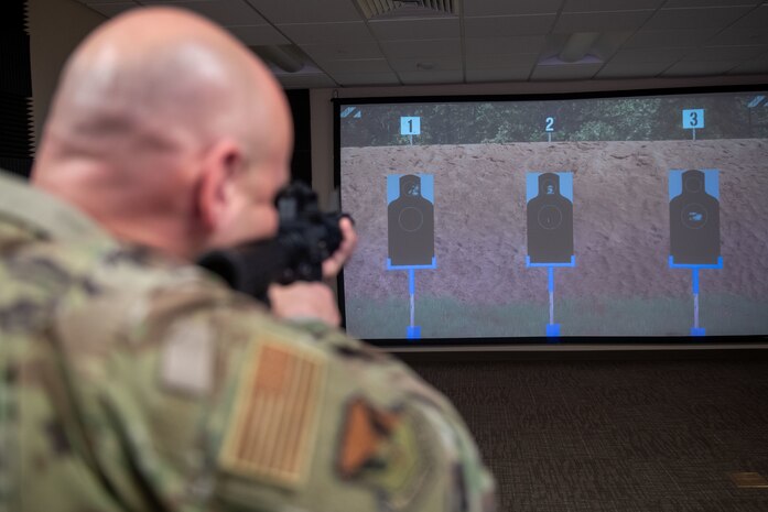 U.S. Air Force Chief Master Sgt. David Snarr, 628th Air Base Wing and Joint Base Charleston command chief, aims an M-4 rifle at a target during firearms simulator training at JB Charleston, South Carolina, Dec. 7, 2023.