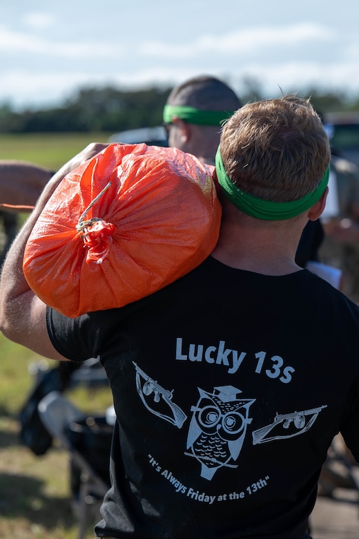 A guardian carries an orange sandbag.