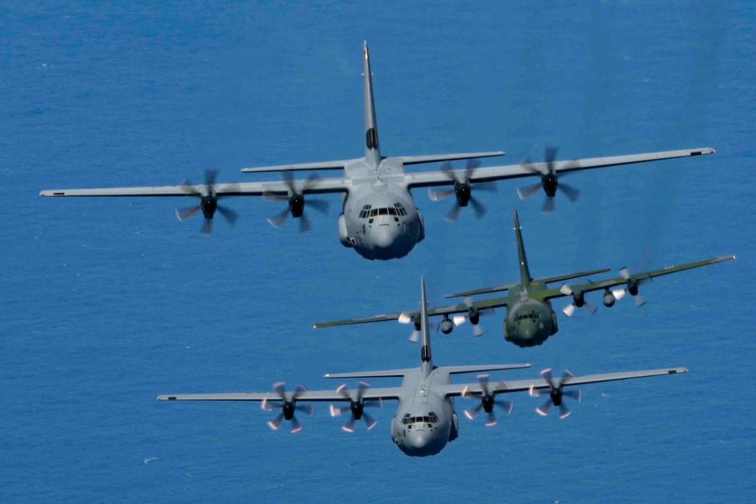 Three aircraft fly in formation over a body of water.
