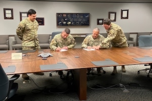 Two men signing document.