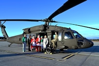 From right, Sgt. Audrey Monroe, a crew chief with A Company, 1-169th Aviation, NHARNG, joins Christine McManus and other volunteers from the State Employees’ Association of New Hampshire on the flight line with a Black Hawk helicopter loaded with donated Christmas gifts Dec. 12 at the Army Aviation Support Facility in Concord.