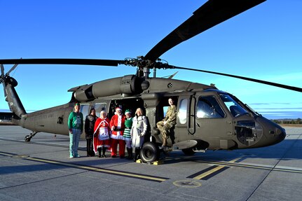 From right, Sgt. Audrey Monroe, a crew chief with A Company, 1-169th Aviation, NHARNG, joins Christine McManus and other volunteers from the State Employees’ Association of New Hampshire on the flight line with a Black Hawk helicopter loaded with donated Christmas gifts Dec. 12 at the Army Aviation Support Facility in Concord.