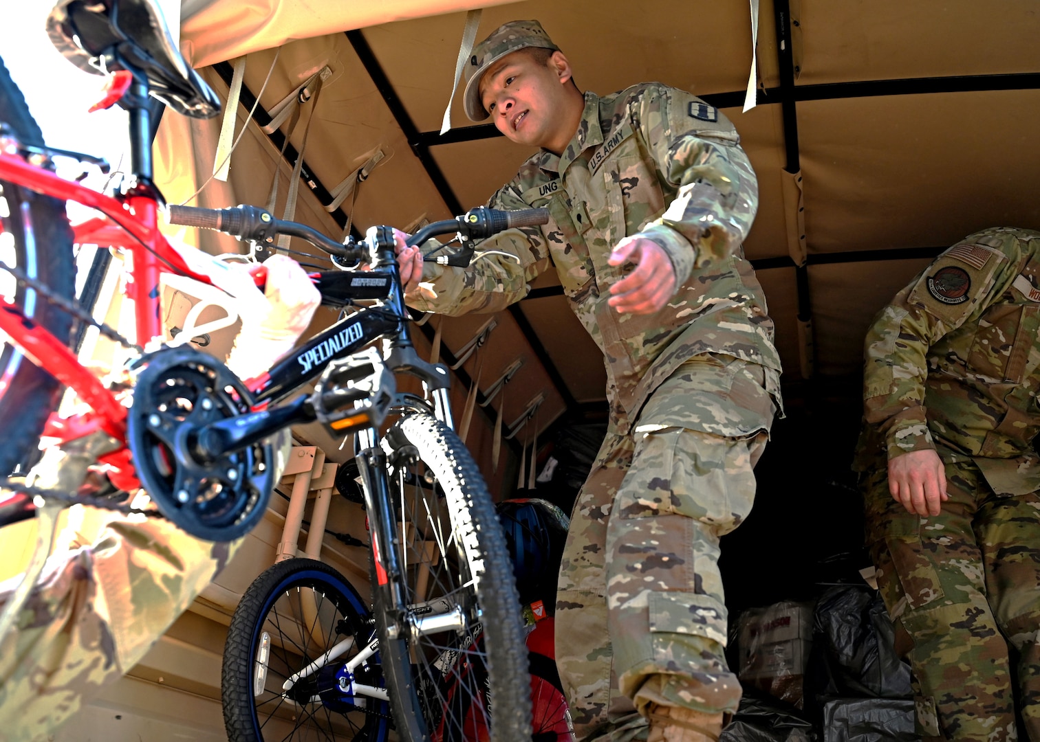 Spc. John Ung, an intelligence analyst with 197th Field Artillery Brigade, NHARNG, helps load a new bicycle onto a military delivery truck Dec. 12, 2023, at the state military reservation in Concord.