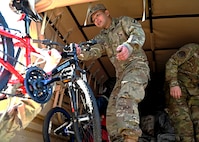 Spc. John Ung, an intelligence analyst with 197th Field Artillery Brigade, NHARNG, helps load a new bicycle onto a military delivery truck Dec. 12, 2023, at the state military reservation in Concord.