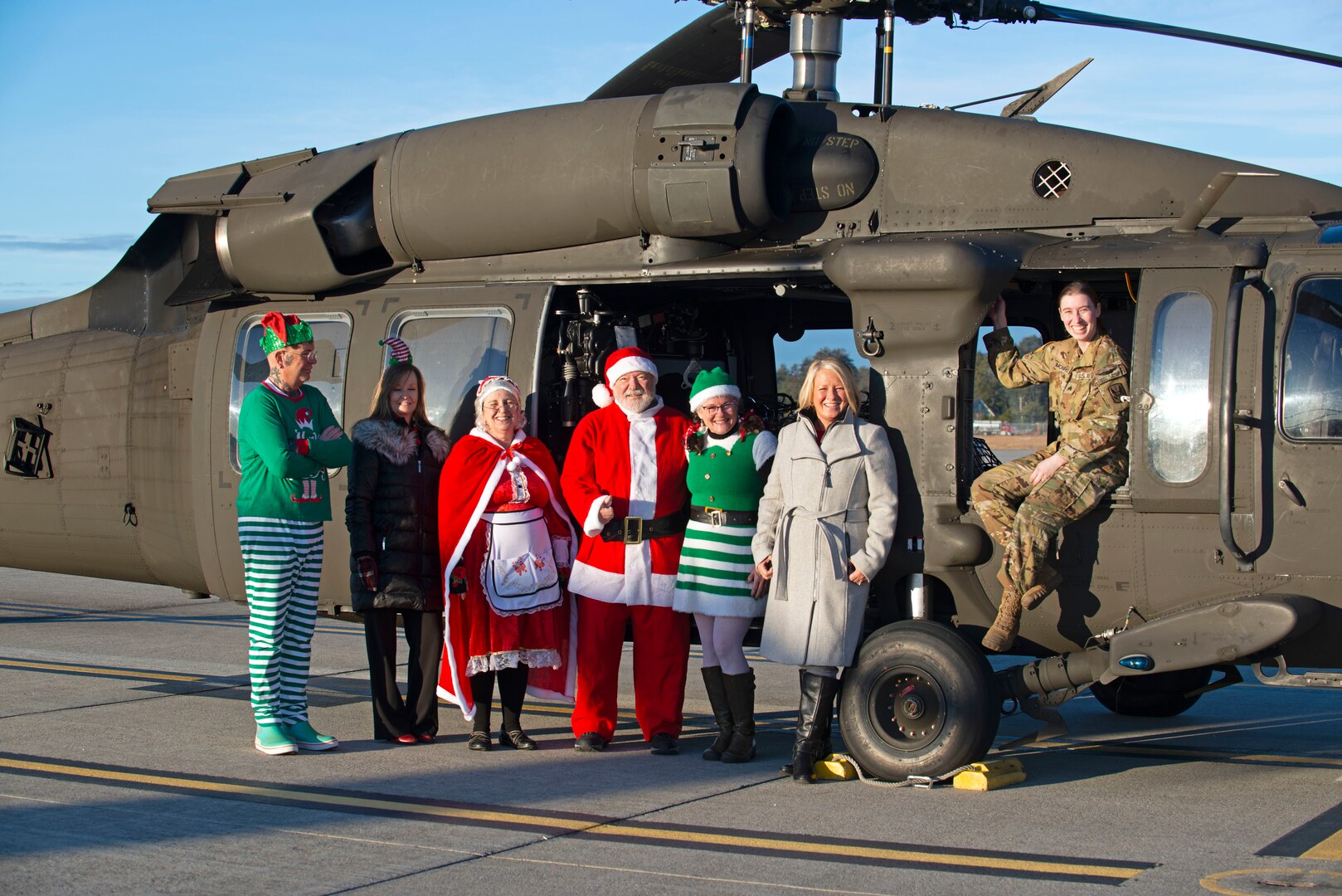 From right, Sgt. Audrey Monroe, a crew chief with A Company, 1-169th Aviation, New Hampshire Army National Guard, joins Christine McManus and volunteers from the State Employees’ Association of N.H. on the flight line with a Black Hawk helicopter loaded with donated Christmas gifts Dec. 12, 2023, at the Army Aviation Support Facility in Concord.