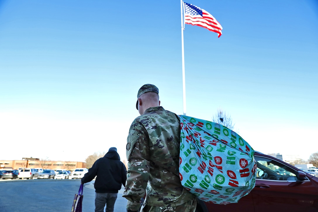 U.S. Army Reserve Staff Sgt. Lucas Swanson, G1, 85th U.S. Army Reserve Support Command, carries a bag full of toys to a vehicle to transport to the Northwest Community Hospital in Arlington Heights, Illinois, December 12, 2023.