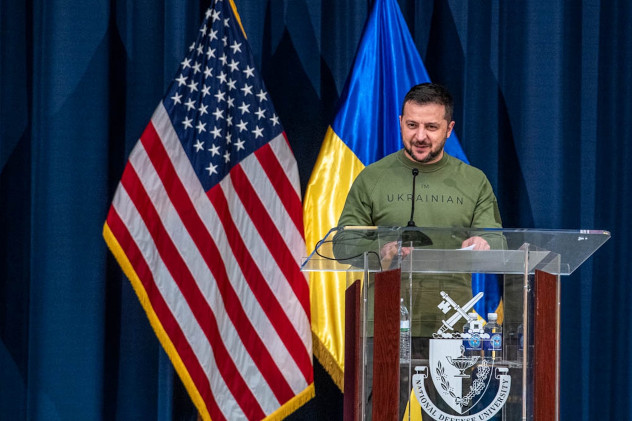 A man in a military uniform is standing at a lectern in front of U.S. and Ukranian flags.