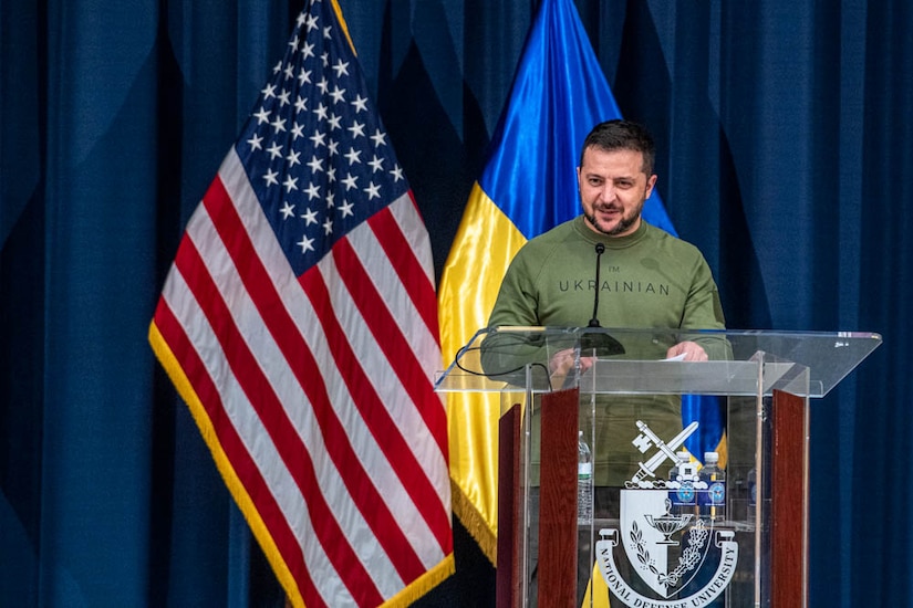 A man in a military uniform is standing at a lectern in front of U.S. and Ukranian flags.