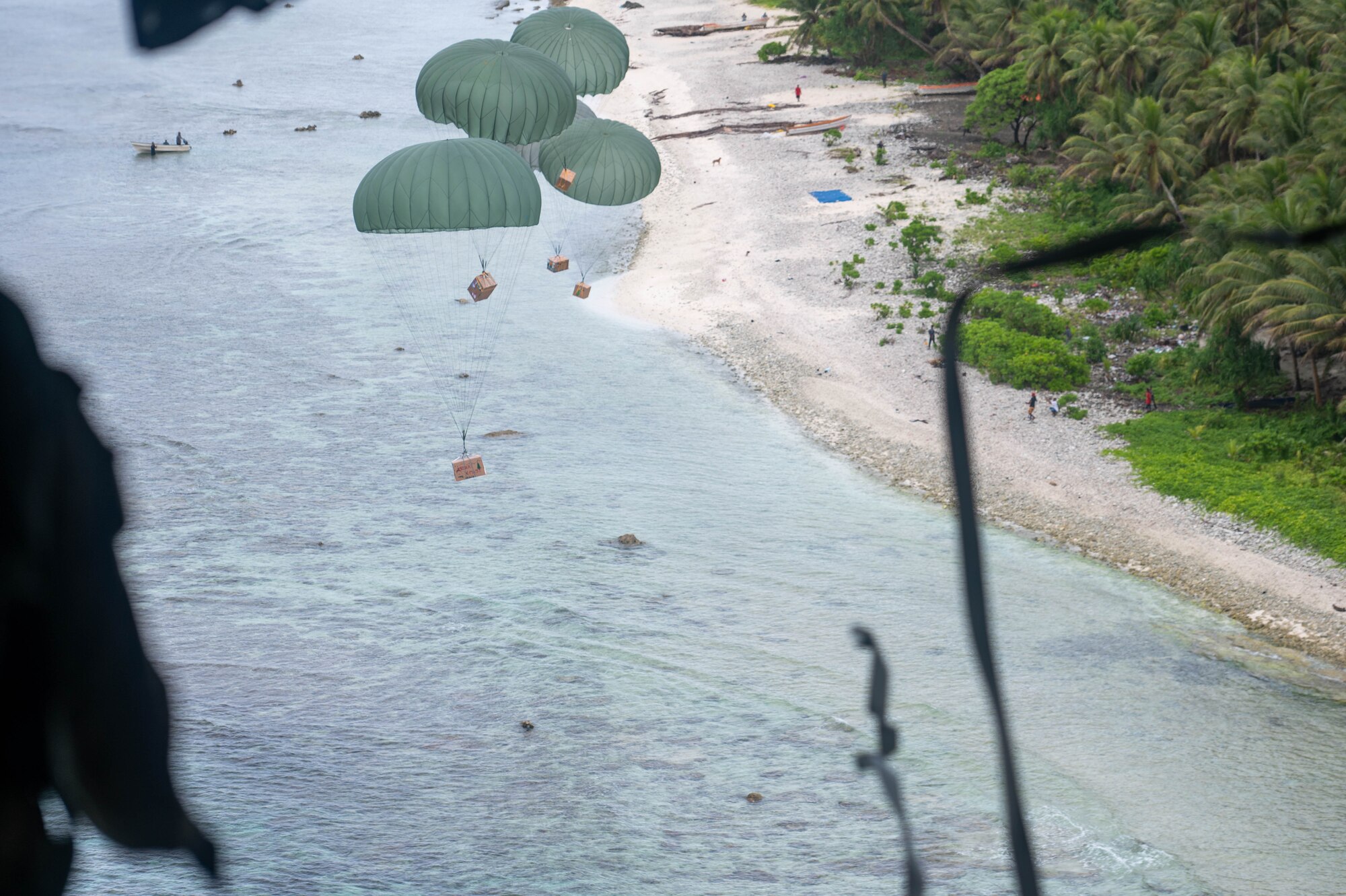Supply bundles land onto shore during Operation Christmas Drop over the island Nama, Dec. 4, 2023. Operation Christmas Drop is the Department of Defense’s longest-running humanitarian airlift operation which consists of packaging and delivering donated supplies such as food, fishing equipment, school books, and clothing to more than 20,000 islanders across 56 remote islands throughout the Federated States of Micronesia and the Republic of Palau. (U.S. Air Force photo by Airman Allon Lapaix)