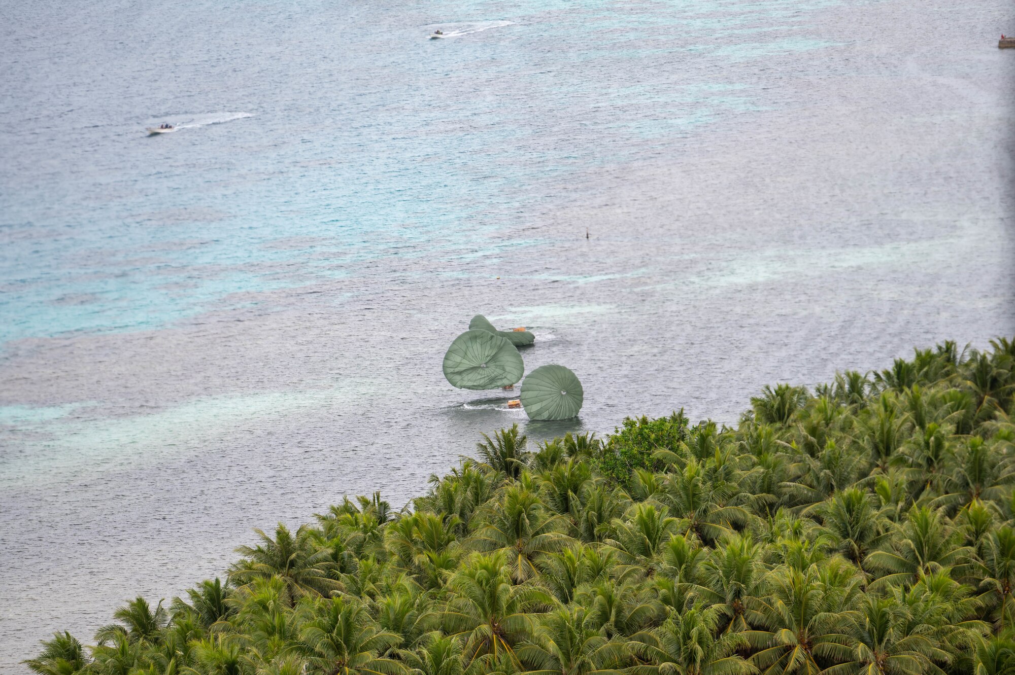 Supply bundles land onto shore during Operation Christmas Drop over the island Nama, Dec. 4, 2023. Operation Christmas Drop is the Department of Defense’s longest-running humanitarian airlift operation which consists of packaging and delivering donated supplies such as food, fishing equipment, school books, and clothing to more than 20,000 islanders across 56 remote islands throughout the Federated States of Micronesia and the Republic of Palau. (U.S. Air Force photo by Airman Allon Lapaix)