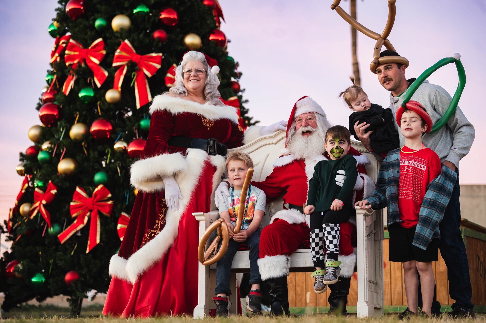 Santa Claus and Mrs. Claus impersonators pose for a photo with service members and their families, Dec. 8, 2023, at Luke Air Force Base, Arizona. Holiday Magic is an annual event with food, games, and holiday cheer for families at Luke AFB.