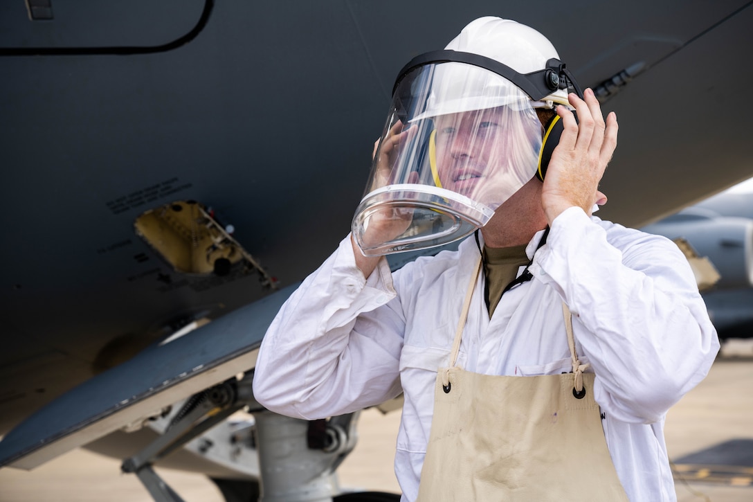 An airman puts protective gear on his head.