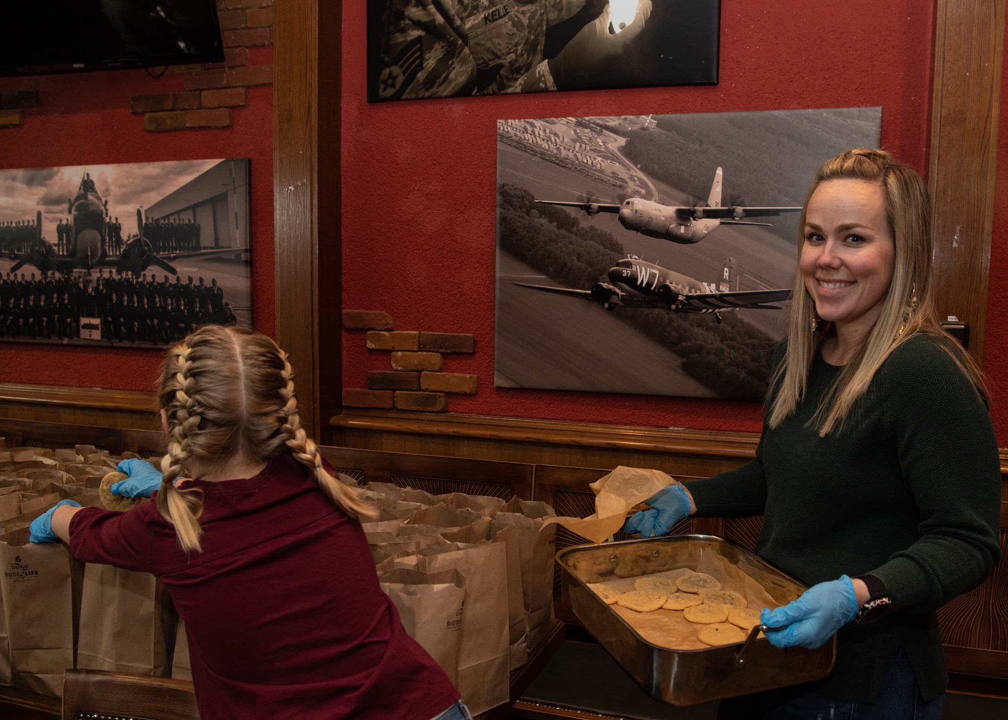 Megan King and her daughter, 2023 Operation Holiday Cheer and Airmen Cookie Drive volunteers, fill paper bags with sugar cookies to be donated to Airmen living in dormitories