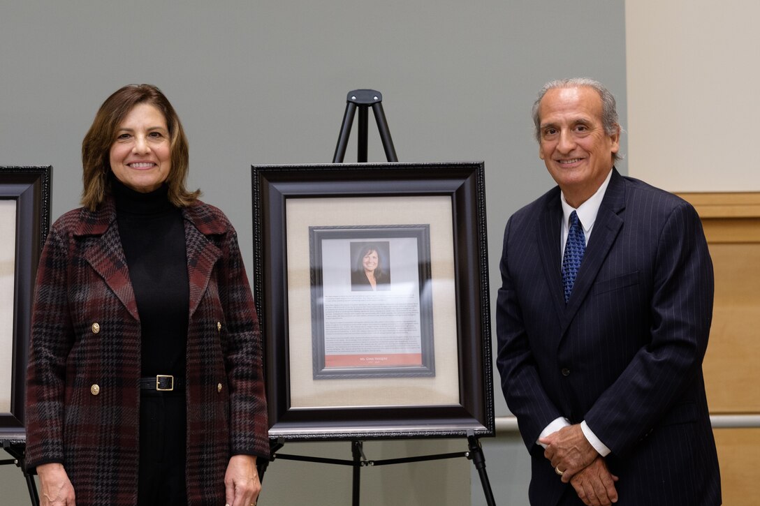 man and woman pose next to plaque on stand