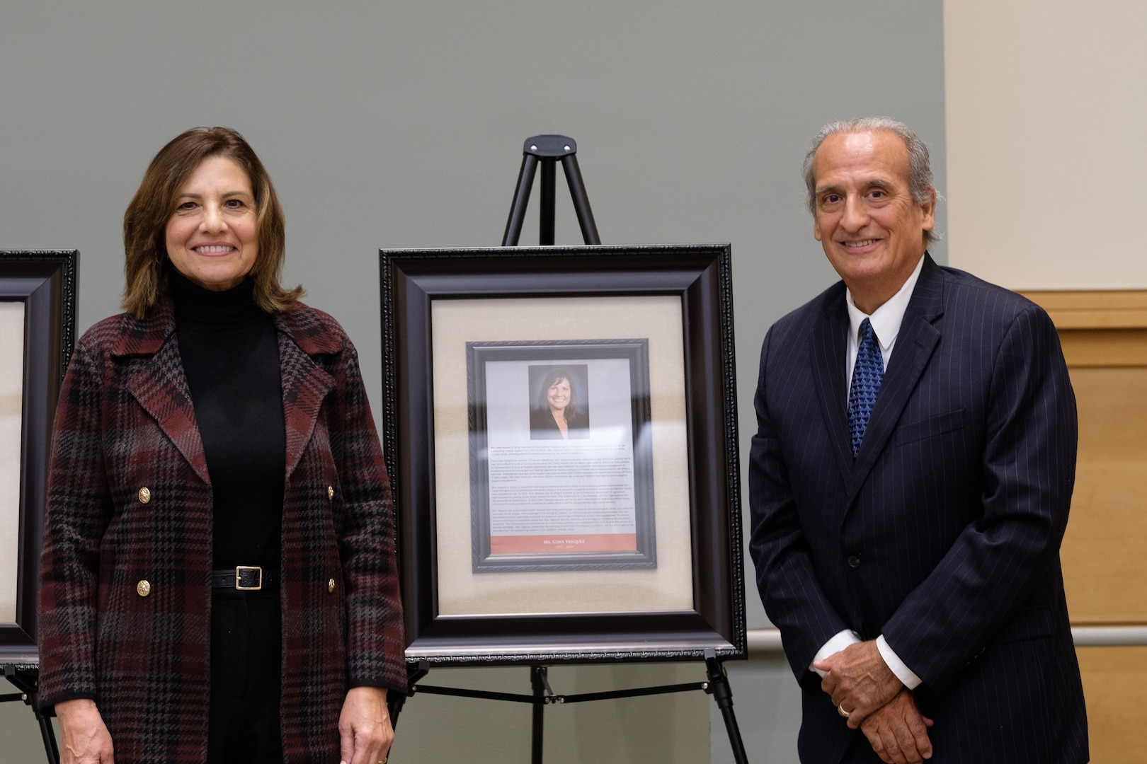 man and woman pose next to plaque on stand