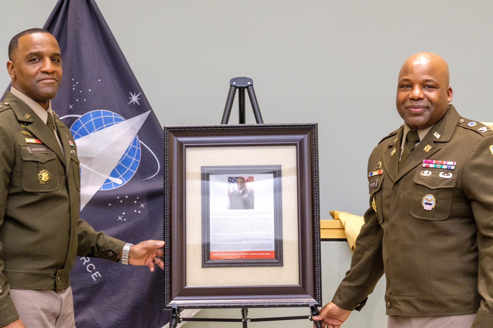 two men in uniform pose next to plaque on stand