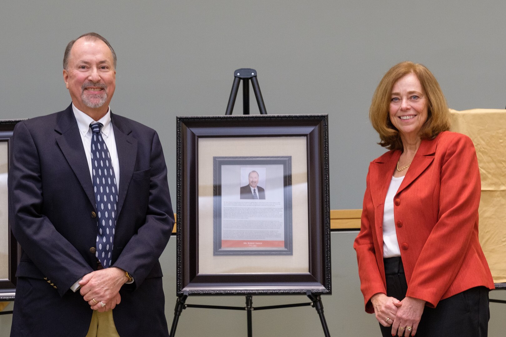 man and woman pose next to plaque on stand