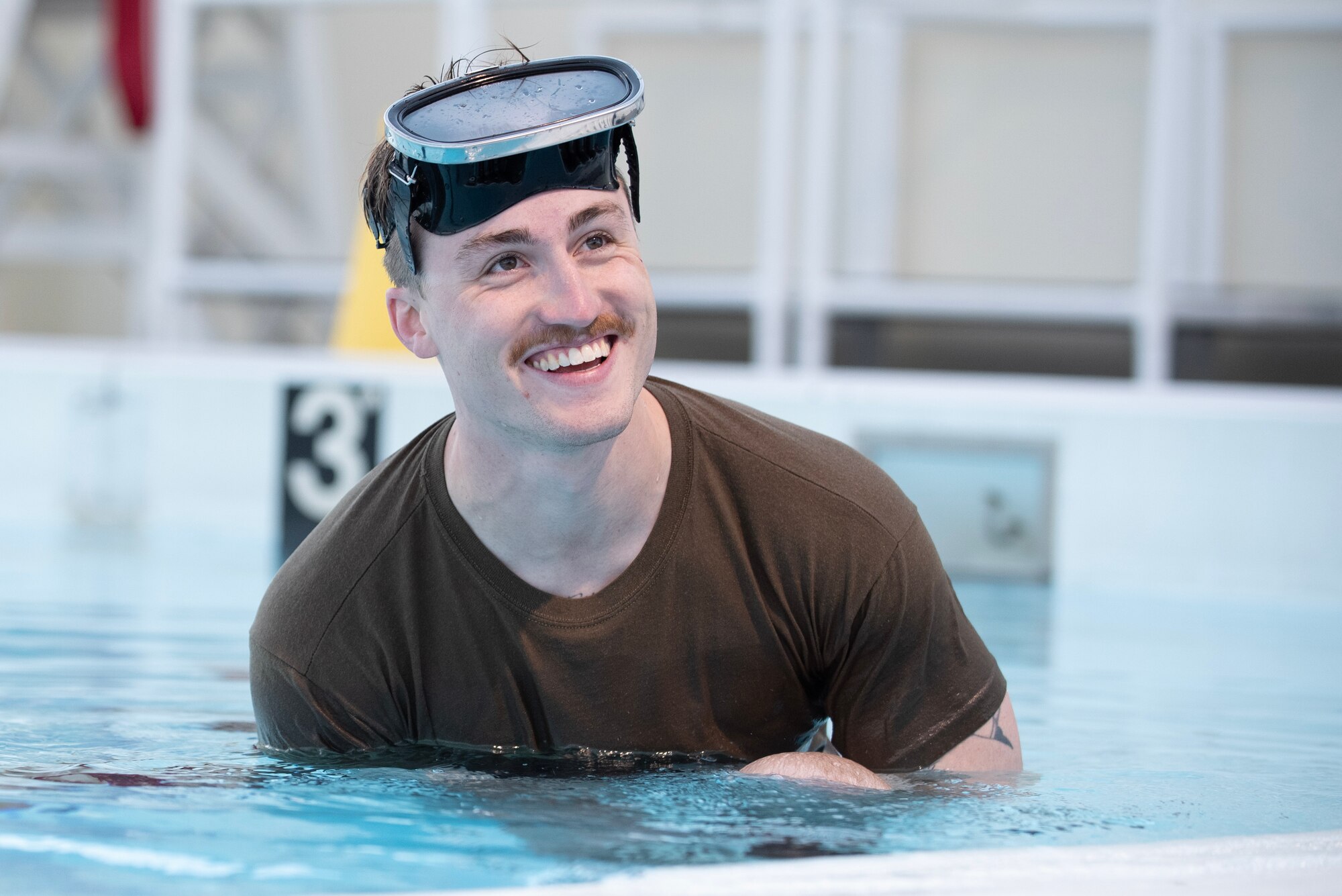 a military member in a pool with goggles on his forhead