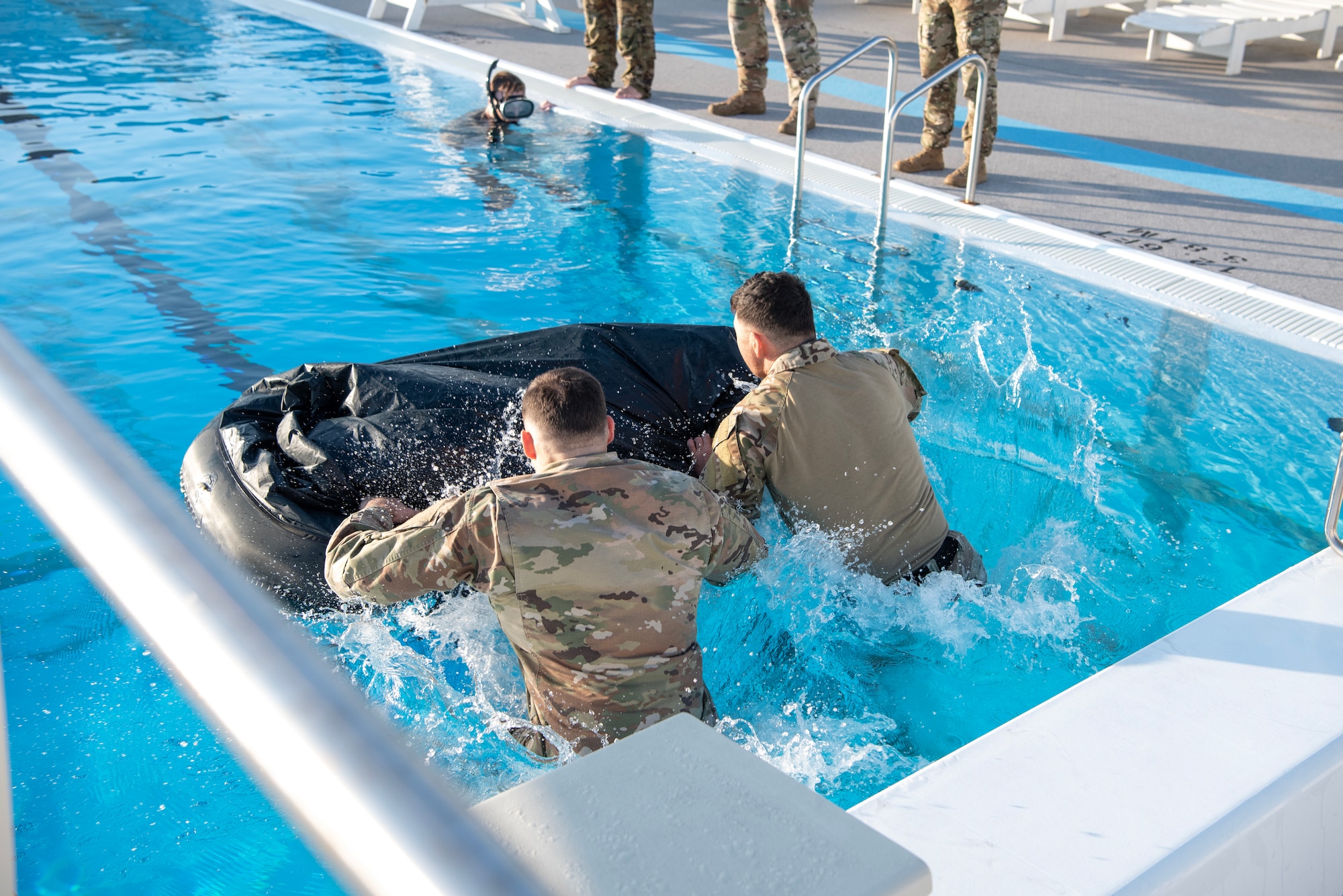 military member jump into a pool and push a raft