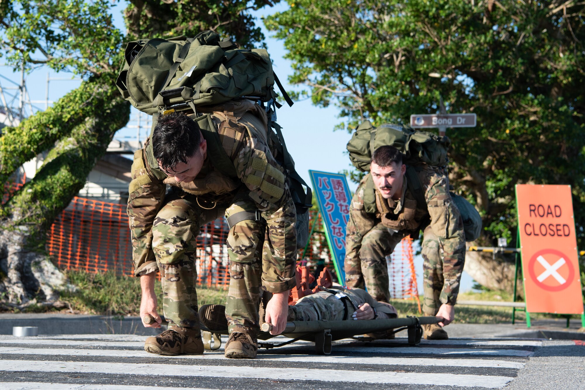 two military members carry a stretcher with another military member laying ontop