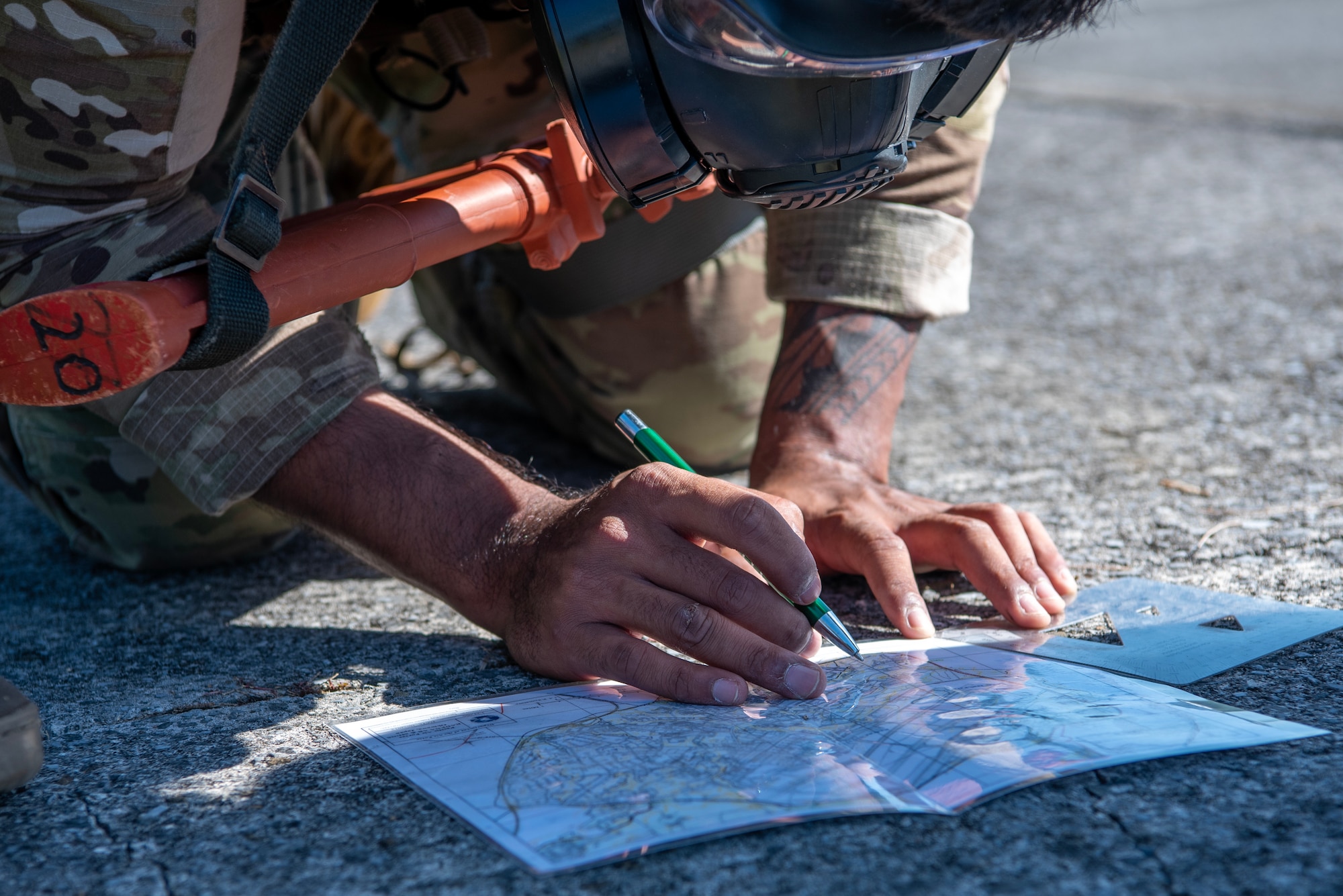 military member on the ground reading a map