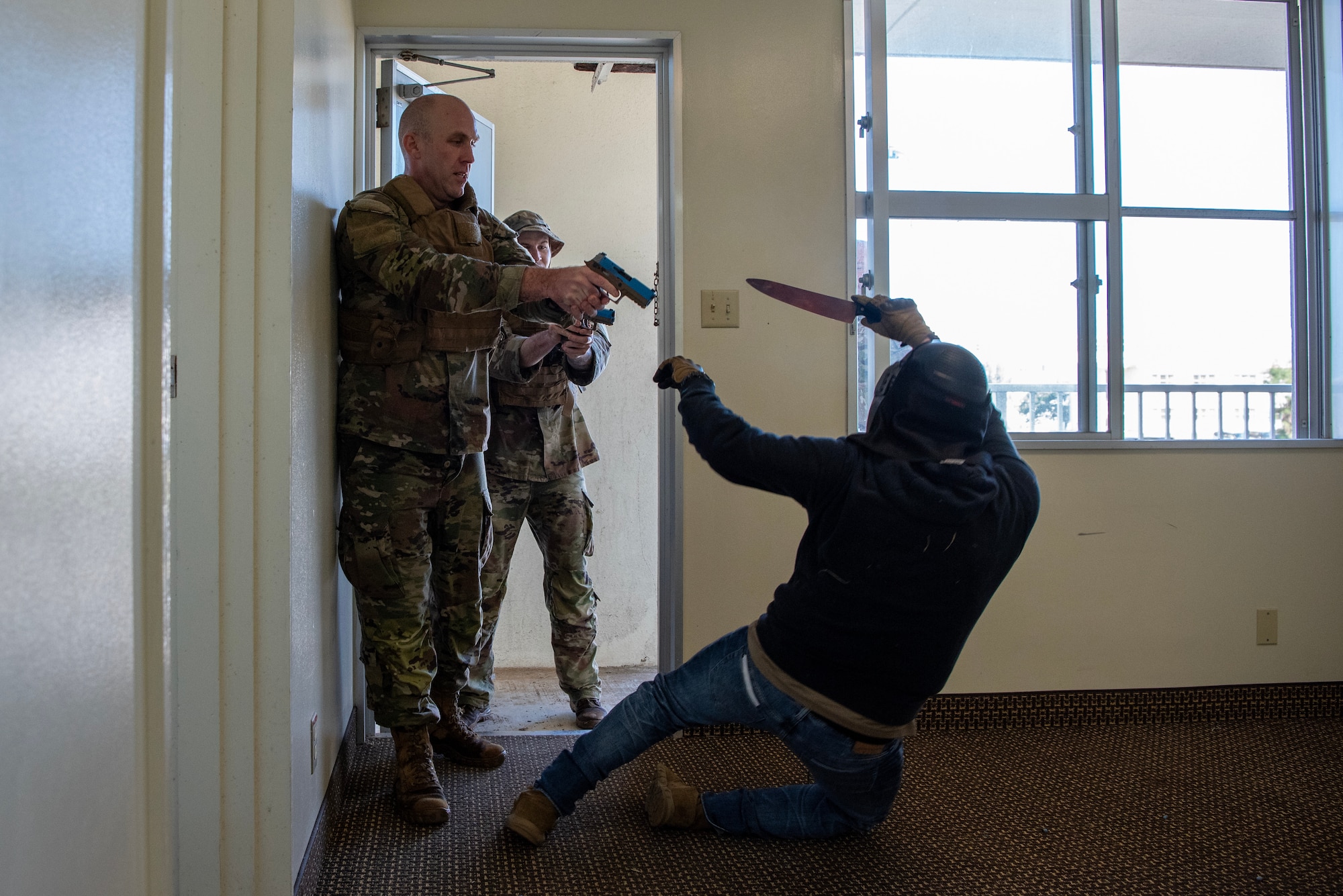 military members enter a room to fire blanks at fake stabbing scenario
