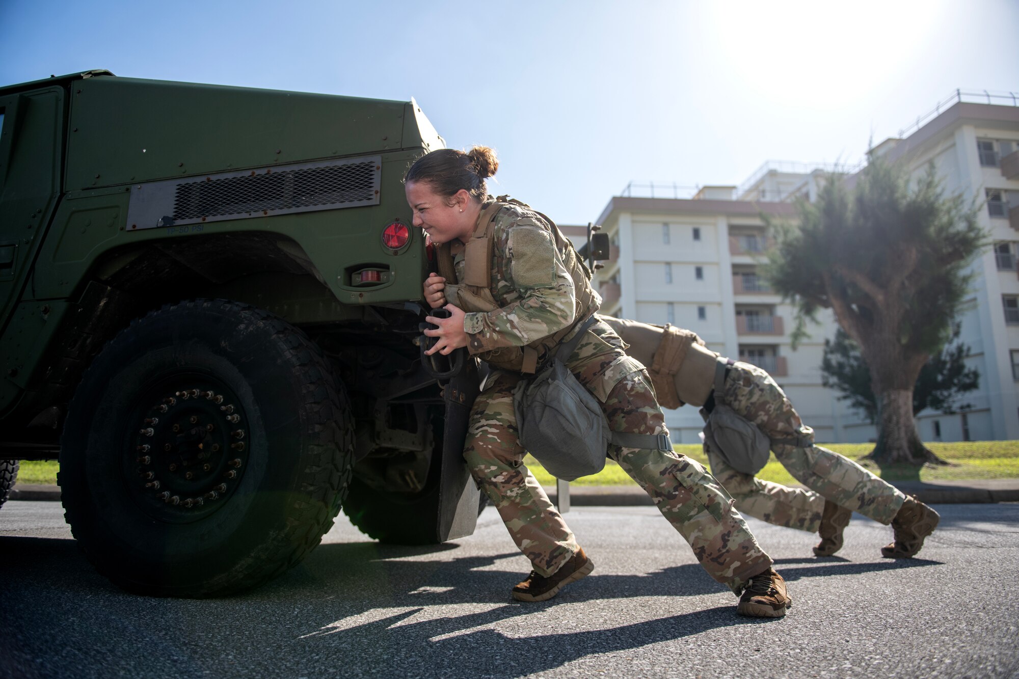 military members push a humvee